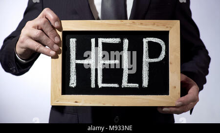 Help written on blackboard, man wearing black suit holding sign, consultation Stock Photo
