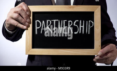 Partnership written on blackboard, businessman holding sign, business concept Stock Photo