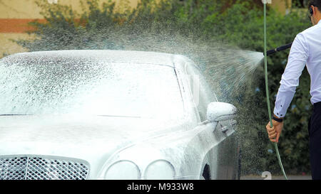 Chauffeur washing luxury automobile with suds, responsible work, business Stock Photo