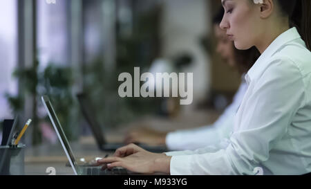 Beautiful woman typing on laptop, working on business project with focused face Stock Photo