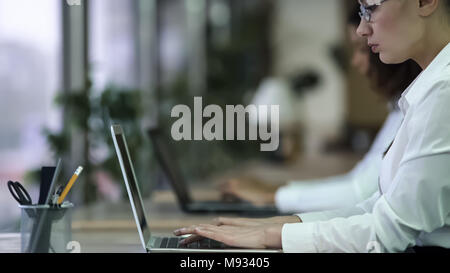 Focused female office employee working on urgent project, missing deadline Stock Photo