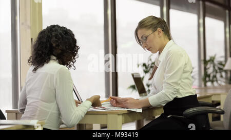 Pretty female employees checking papers, office team working on project together Stock Photo