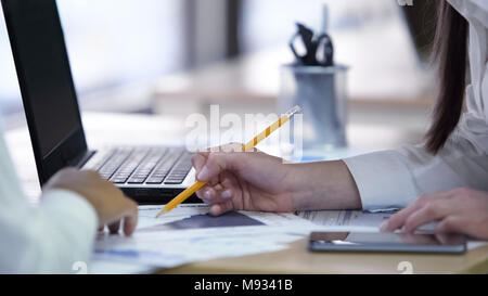 Two women discussing project and working on papers together at company office Stock Photo