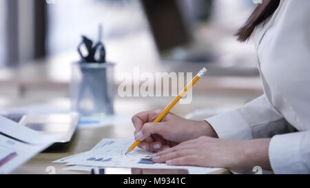 Smart female office worker busy checking documents, making notes on diagrams Stock Photo