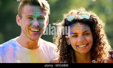 Smiling couple having fun outside on color party celebration, enjoying festival Stock Photo
