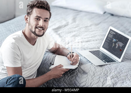 Nice positive man holding his notebook Stock Photo