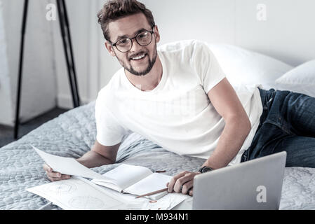 Delighted positive man lying on the bed Stock Photo