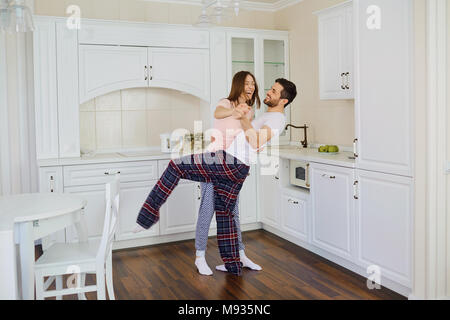A young couple in their pajamas is dancing fun in the kitchen. Stock Photo