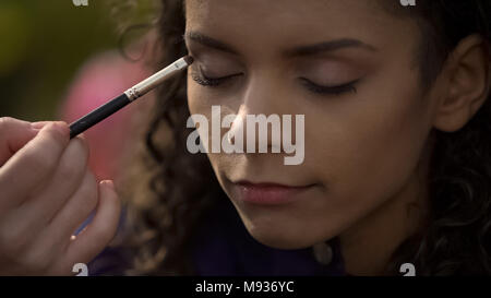 Woman making smoky eyes makeup, preparing beautiful actress for film shooting Stock Photo