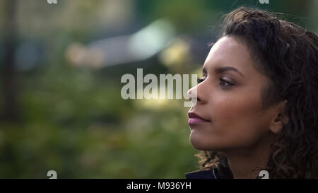 Dreamy biracial curly haired woman looking afar, thinking about life, closeup Stock Photo