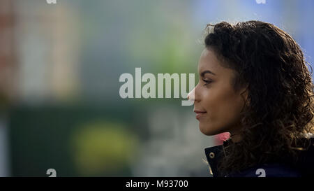 Inspired female model smiling, beautiful biracial young lady portrait in profile Stock Photo