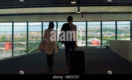 Couple in formal wear walking with bags in airport, business trip, partners Stock Photo