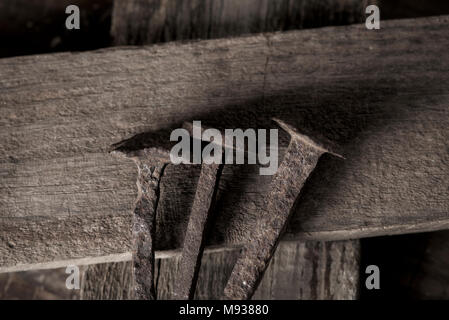 closeup of three rusty nails on a wooden cross, depicting the holy nails and the holy cross Stock Photo