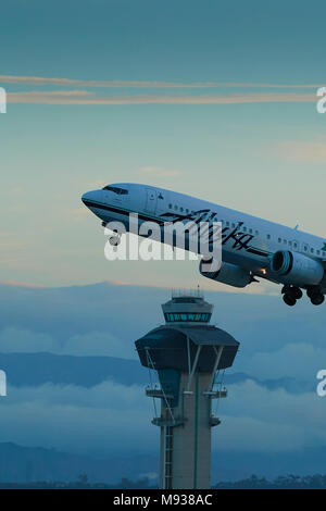 Alaska Airlines Boeing 737-900 Passenger Jet Taking Off From LAX, Los Angeles International Airport, The Control Tower With Cloud And Mist Behind. Stock Photo