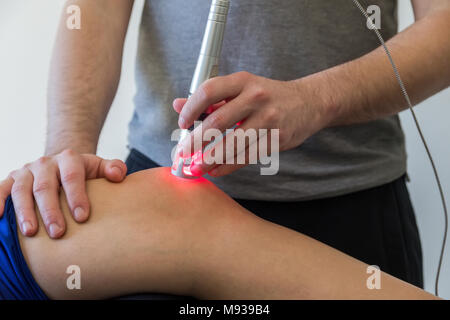 Laser therapy on a knee used to treat pain. selective focus Stock Photo