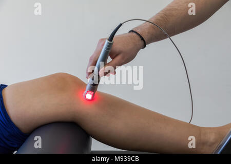 Laser therapy on a knee used to treat pain. selective focus Stock Photo