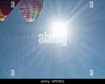 Paragliding: Paraglider with sun and blue sky in background Stock Photo