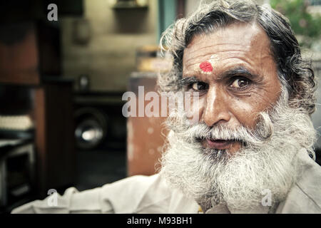 Portrait of Indian man with a classic handlebar moustache and white beard with red tikka dot on forehead. Somewhat stereotypical Indian character Stock Photo