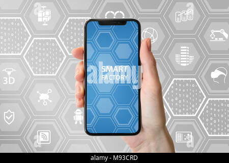 Smart factory concept with symbols. Hand holding bezel free smart phone. Stock Photo