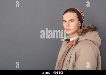 Young guy wearing winter clothes studio isolated on grey wall looking camera serious side view Stock Photo