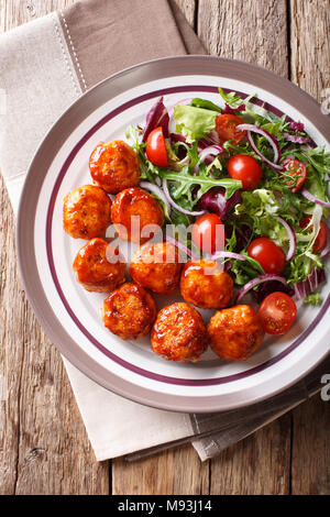 Delicious food: fried chicken meatballs salad of tomato, lettuce and onion close-up on a plate on the table. Vertical top view from above Stock Photo