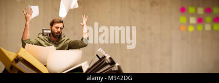 Composite image of frustrated businessman throwing paper while sitting at table Stock Photo