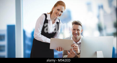 Composite image of portrait of smiling colleagues at table Stock Photo