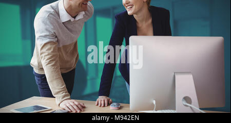 Composite image of smiling colleagues discussing over computer at table Stock Photo