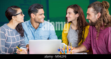 Composite image of colleagues discussing over laptop while sitting at desk Stock Photo