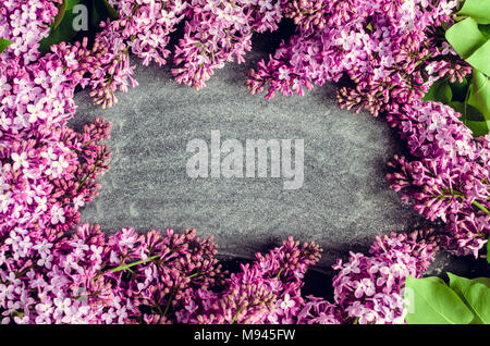 Frame of beautiful spring flowers lilac on chalkboard background with place for text. Syringa vulgaris. Happy Mother's Day greetings card. Top view. C Stock Photo