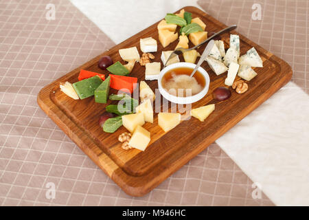 Cheese plates served with grapes, jam and nuts. Cheese allsorts. Dorblu cheese, Camembert, Parmesan, Suluguni. Close-up Stock Photo