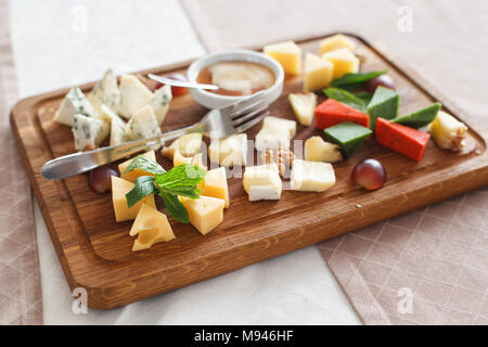 Cheese plates served with grapes, jam and nuts. Cheese allsorts. Dorblu cheese, Camembert, Parmesan, Suluguni. Close-up Stock Photo