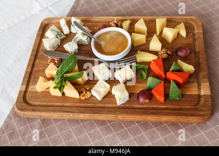 Cheese plates served with grapes, jam and nuts. Cheese allsorts. Dorblu cheese, Camembert, Parmesan, Suluguni. Close-up Stock Photo