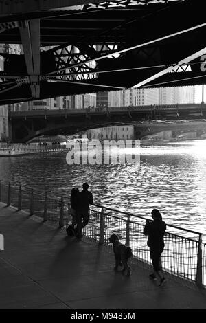 The late afternoon sun silhouettes people walking along Chicago's downtown Riverwalk. Stock Photo