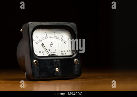 Closeup of an old black analog ampere meter on a wooden table Stock Photo