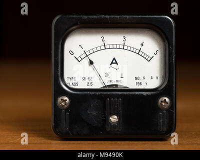Closeup of an old black analog ampere meter on a wooden table Stock Photo