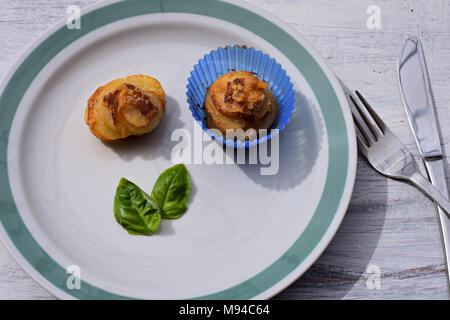 Freshly baked homemade muffin potatoes whit bacon and basil served at plate at white background Stock Photo
