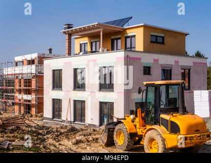 A new building next to a shell in a construction area with a wheel loader in the foreground Stock Photo