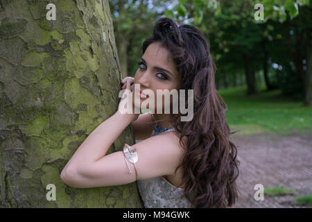 Beautiful young Asian woman leaning against a tree Stock Photo