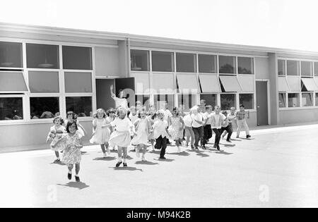 Elementary students head out the school door and class in California, ca. 1965. Stock Photo