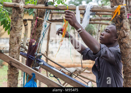 Kouassi, age 15, works at a small weaving factory in Gbomi Kondeyaokro, central Côte d'Ivoire. He is an Akan, famous for their Kente cloth (known as nwentom in Akan) which a type of silk and cotton fabric made of interwoven cloth strips. Stock Photo