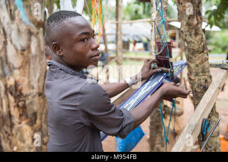 Kouassi, age 15, works at a small weaving factory in Gbomi Kondeyaokro, central Côte d'Ivoire. He is an Akan, famous for their Kente cloth (known as nwentom in Akan) which a type of silk and cotton fabric made of interwoven cloth strips. Stock Photo