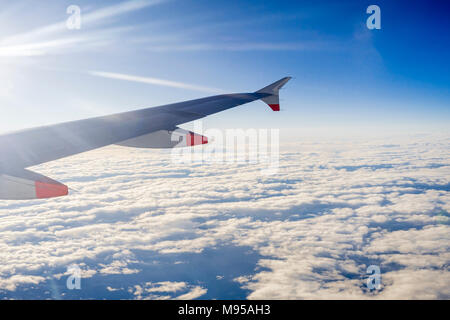 View from an airplane window in mid flight to the airplane wing with blue sky and stratocumulus clouds visible Stock Photo