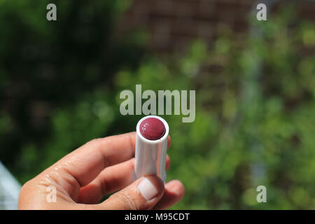 Close up of hand holding red colour lip gloss Stock Photo