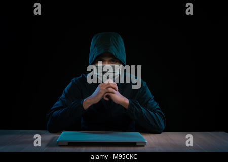 Asian hacker hacking computer network with laptop in dark. Cyber security concept Stock Photo