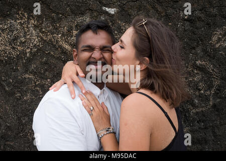 Outdoor portrait of romantic kissing young couple in sandy beach. Concept of honeymoon and true love Stock Photo