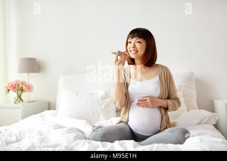 pregnant woman using voice recorder on smartphone Stock Photo
