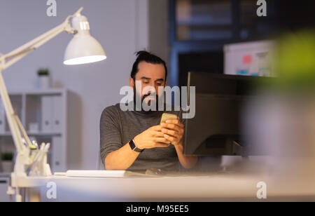 creative man with smartphone at night office Stock Photo