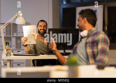 creative man showing papers to colleague at office Stock Photo