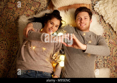 happy couple lying on floor and making hand heart Stock Photo